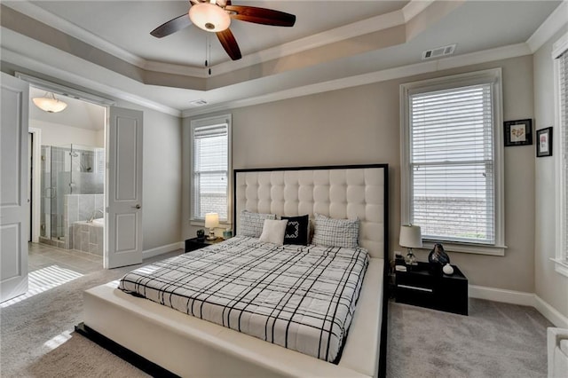 carpeted bedroom with baseboards, crown molding, connected bathroom, visible vents, and a raised ceiling