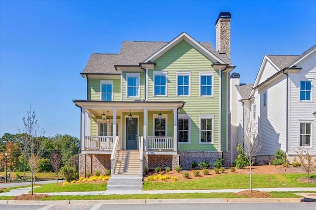 view of front of property with stairs, a chimney, a porch, and a front yard