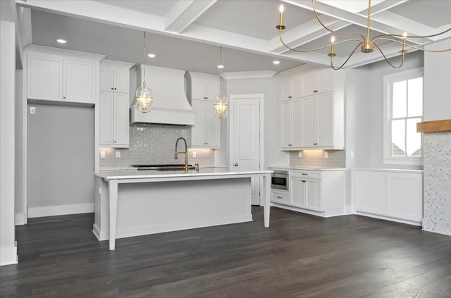 kitchen with custom range hood, dark hardwood / wood-style flooring, a center island with sink, and white cabinetry