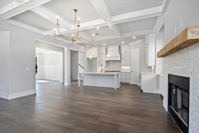 unfurnished living room featuring beam ceiling, dark hardwood / wood-style flooring, a fireplace, and coffered ceiling