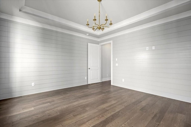 spare room featuring a tray ceiling, dark hardwood / wood-style flooring, and a chandelier