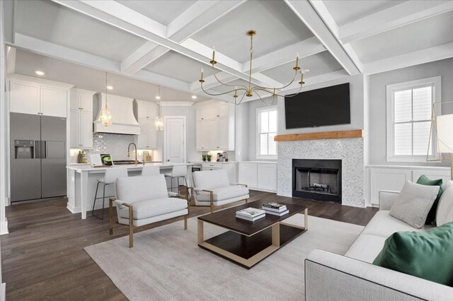 living room featuring sink, coffered ceiling, beamed ceiling, a chandelier, and wood-type flooring