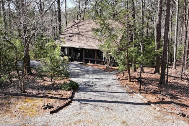 chalet / cabin with a porch, driveway, and a wooded view