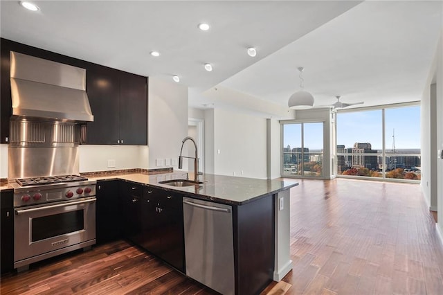 kitchen with wall chimney range hood, stainless steel appliances, dark wood-type flooring, and sink