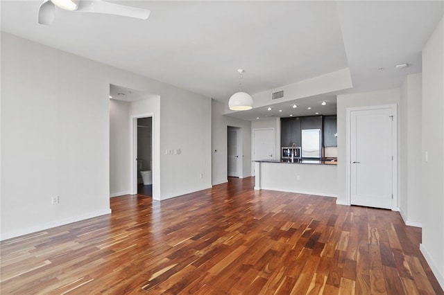 unfurnished living room featuring ceiling fan and dark hardwood / wood-style floors