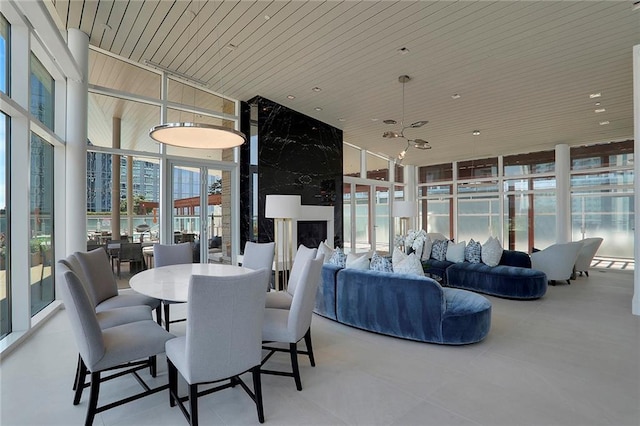 dining room featuring plenty of natural light, a wall of windows, wooden ceiling, and ceiling fan