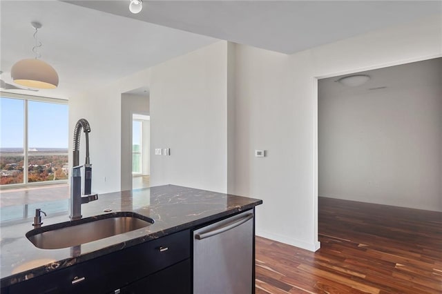 kitchen with dishwasher, dark wood-type flooring, dark stone counters, sink, and hanging light fixtures