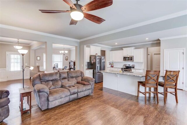 living room with dark hardwood / wood-style flooring, sink, ceiling fan with notable chandelier, and crown molding