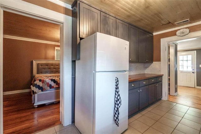 245 Alcovy St, Monroe, GA 30655 - kitchen with dark brown cabinets, white refrigerator, light tile patterned floors, wood ceiling, and decorative backsplash