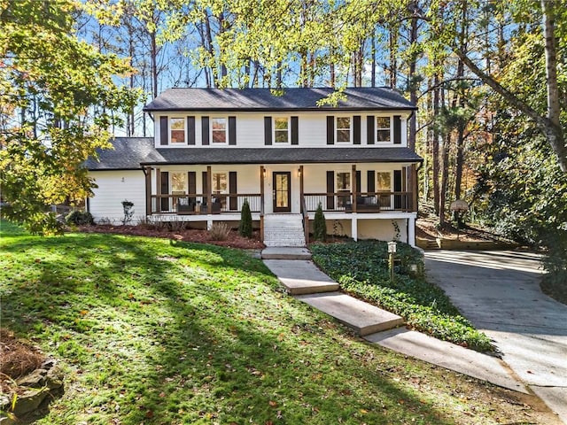 view of front of house featuring a garage, covered porch, and a front lawn