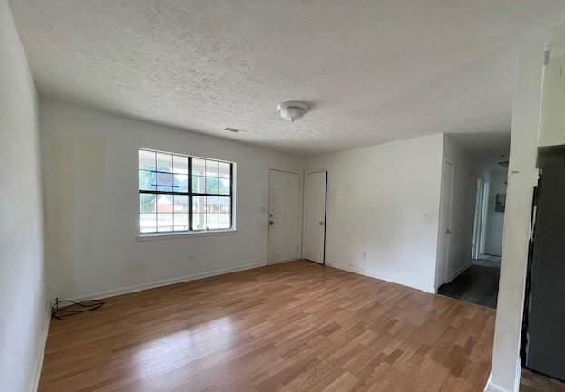 empty room featuring wood-type flooring and a textured ceiling