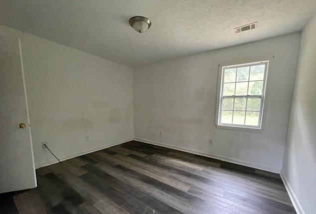 unfurnished room with a textured ceiling and dark hardwood / wood-style flooring