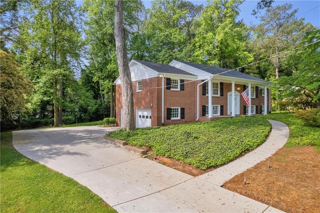 4331 E Kings Point Cir, Dunwoody, GA 30338 - greek revival inspired property featuring concrete driveway, a garage, brick siding, and view of scattered trees