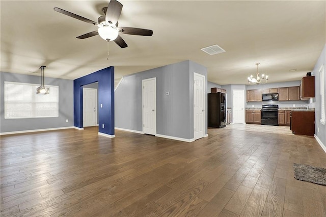 unfurnished living room with sink, dark wood-type flooring, and ceiling fan with notable chandelier