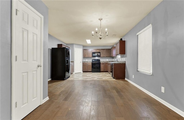 kitchen with pendant lighting, black appliances, sink, light hardwood / wood-style floors, and a chandelier