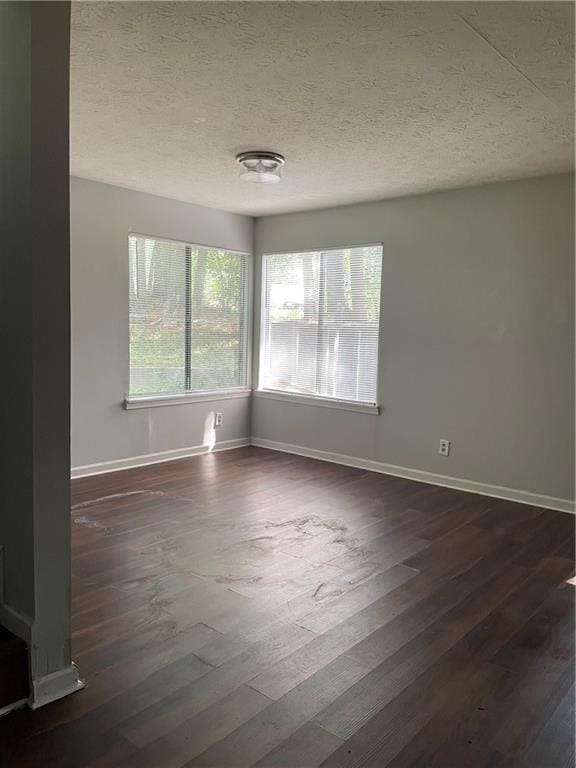 unfurnished room with a textured ceiling, dark hardwood / wood-style flooring, and a healthy amount of sunlight