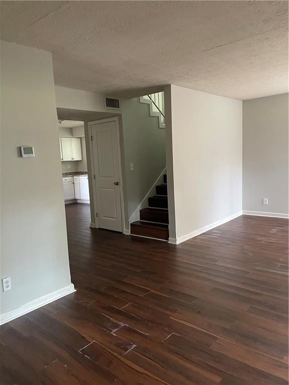 spare room featuring dark hardwood / wood-style flooring and a textured ceiling