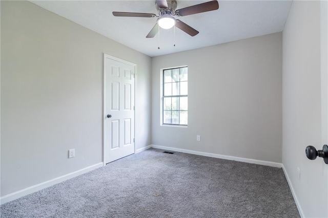 carpeted spare room with ceiling fan, visible vents, and baseboards