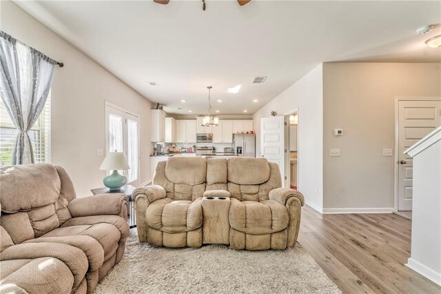 living room with ceiling fan, a wealth of natural light, and light hardwood / wood-style flooring