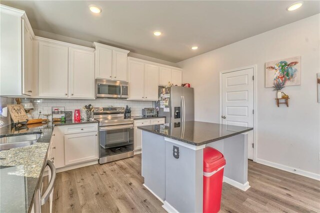 kitchen with white cabinets, a center island, appliances with stainless steel finishes, and light hardwood / wood-style flooring