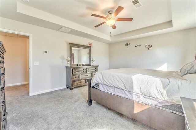 bedroom featuring ceiling fan, a raised ceiling, and light carpet