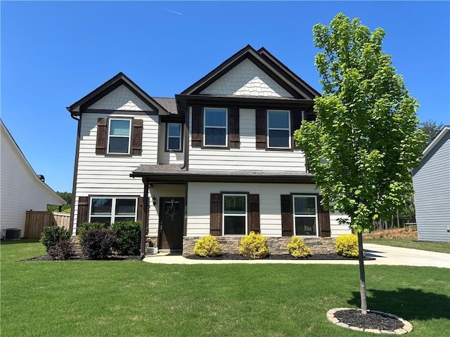 craftsman house with central AC, stone siding, a front yard, and fence