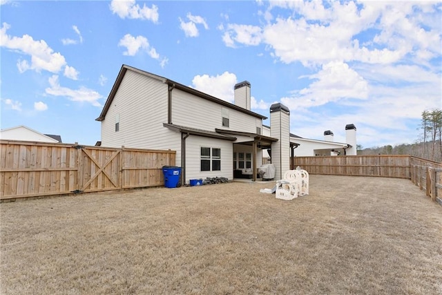 back of property with a gate, a chimney, and a fenced backyard