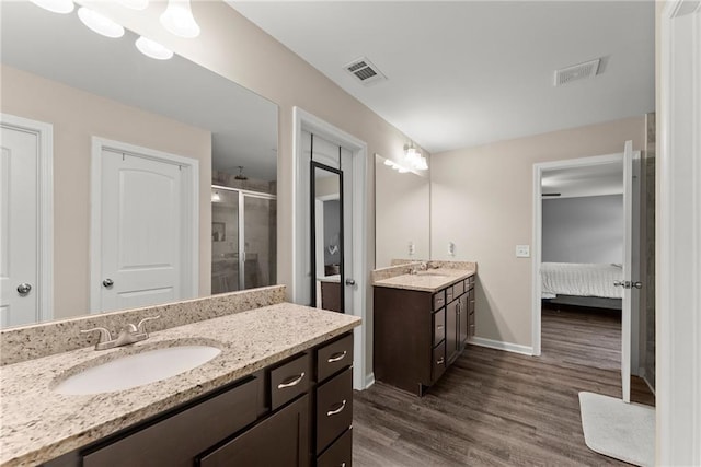 ensuite bathroom featuring a sink, a stall shower, wood finished floors, and visible vents