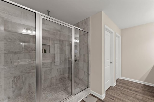 bathroom with baseboards, a shower stall, and wood finished floors