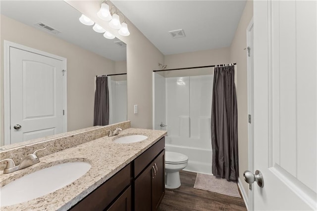 full bath featuring double vanity, a sink, wood finished floors, and visible vents