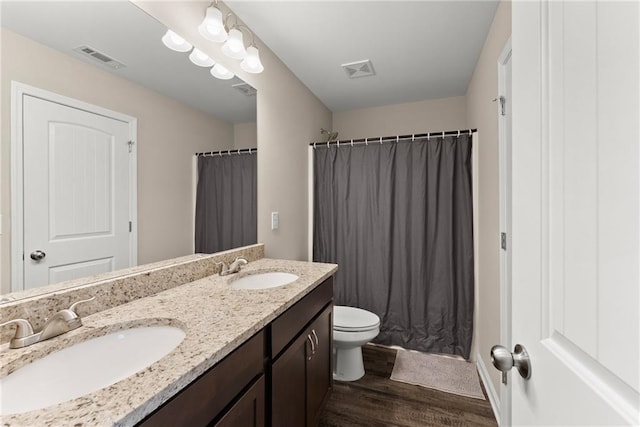 bathroom with visible vents, a sink, wood finished floors, and double vanity