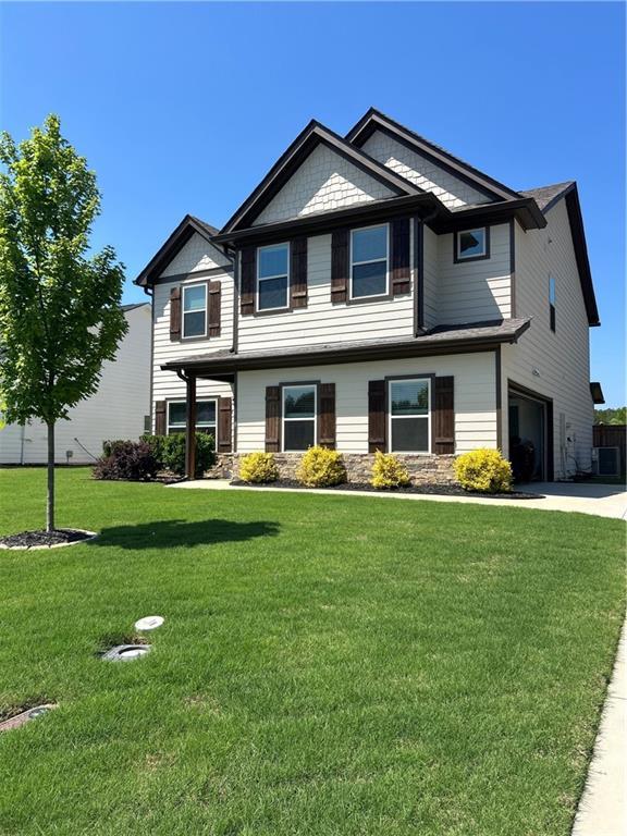craftsman-style house with an attached garage, driveway, a front lawn, and stone siding