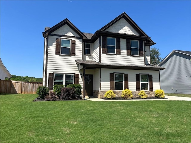 view of front facade with fence, stone siding, and a front yard