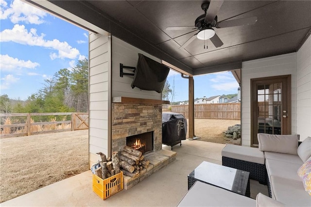view of patio / terrace with a fenced backyard, a ceiling fan, an outdoor living space with a fireplace, and area for grilling