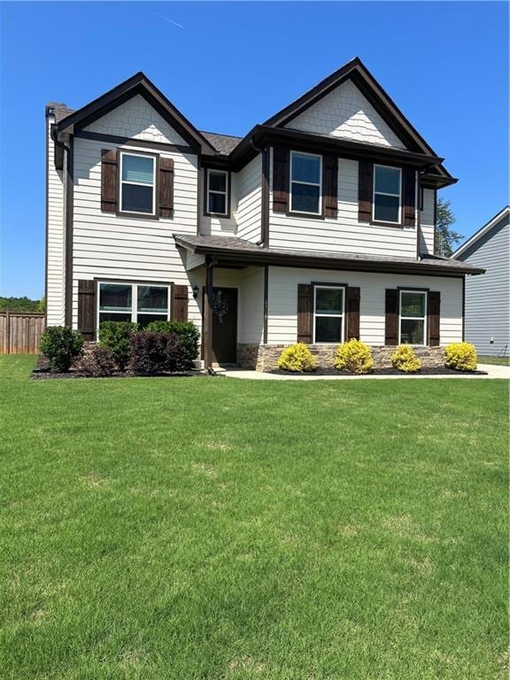 craftsman-style home featuring fence, a front yard, and stone siding