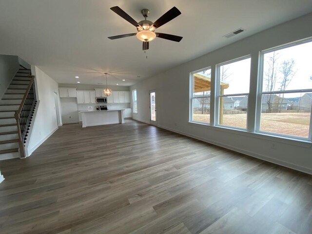 unfurnished living room with dark hardwood / wood-style floors, plenty of natural light, and ceiling fan