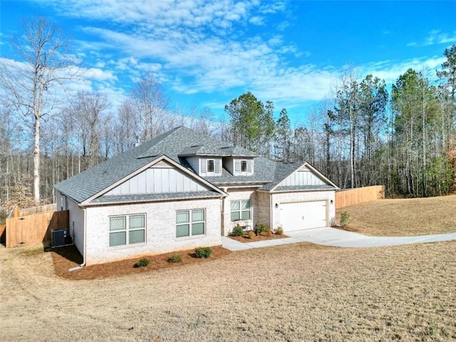 view of front of home featuring a garage, cooling unit, and a front yard