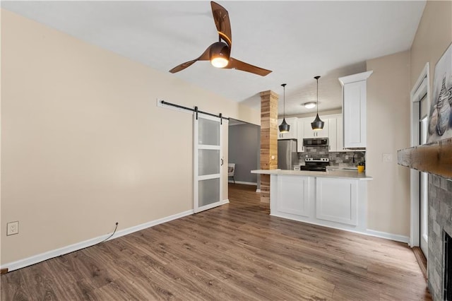 2680 Pine Tree Rd NE Unit 2, Atlanta, GA 30324 - kitchen featuring stainless steel appliances, a barn door, decorative backsplash, white cabinetry, and wood finished floors