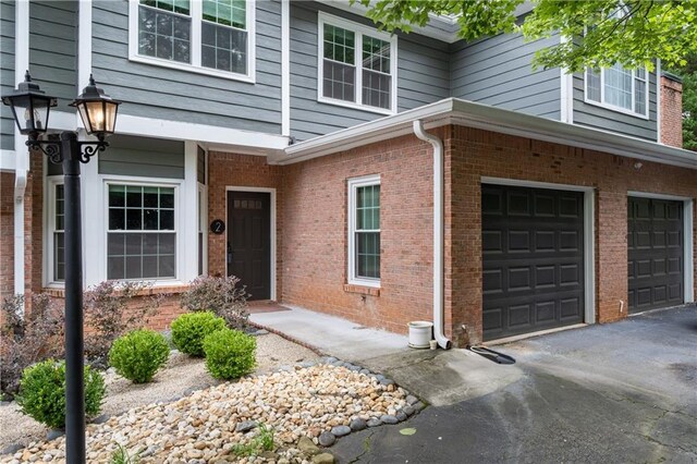 2680 Pine Tree Rd NE Unit 2, Atlanta, GA 30324 - view of exterior entry with an attached garage, brick siding, and driveway