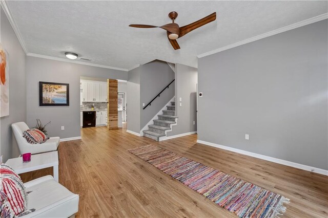 2680 Pine Tree Rd NE Unit 2, Atlanta, GA 30324 - living room featuring stairway, a ceiling fan, light wood-type flooring, crown molding, and a textured ceiling