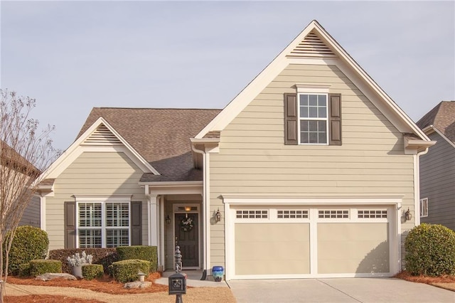 traditional home featuring a garage, concrete driveway, and a shingled roof