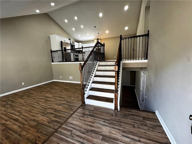 stairs with high vaulted ceiling, baseboards, and wood finished floors