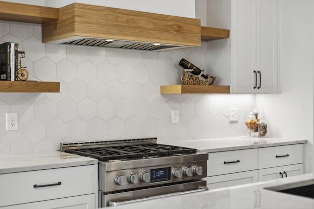 kitchen featuring white cabinetry, premium range hood, high end range, tasteful backsplash, and light stone counters