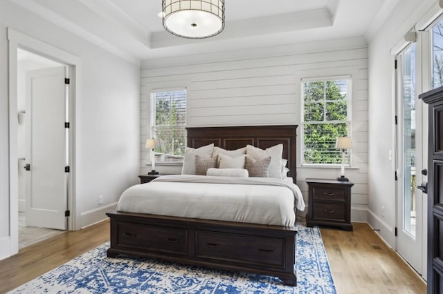 bedroom with a tray ceiling and light wood-type flooring