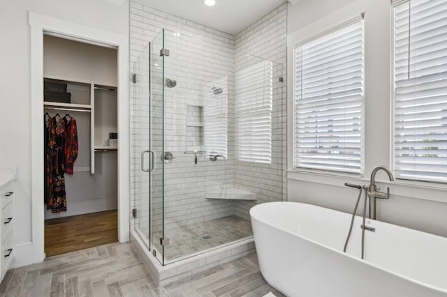 bathroom with wood-type flooring, plus walk in shower, and vanity