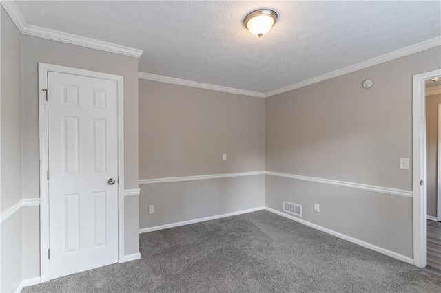 spare room with a textured ceiling, dark carpet, and ornamental molding