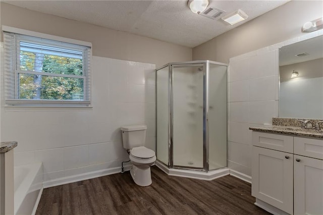 full bathroom with wood-type flooring, toilet, a textured ceiling, vanity, and independent shower and bath