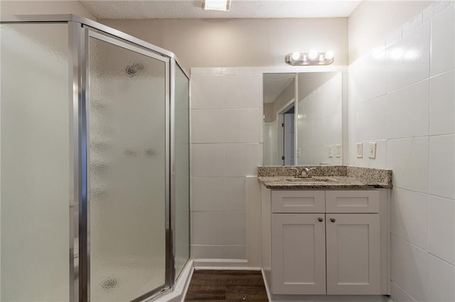 bathroom featuring tile walls, walk in shower, wood-type flooring, and vanity