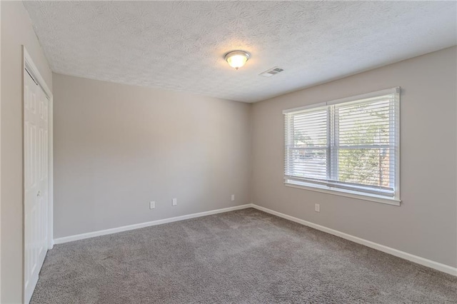 carpeted spare room featuring a textured ceiling