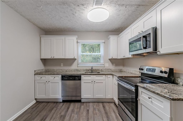 kitchen with white cabinets, appliances with stainless steel finishes, and light hardwood / wood-style flooring